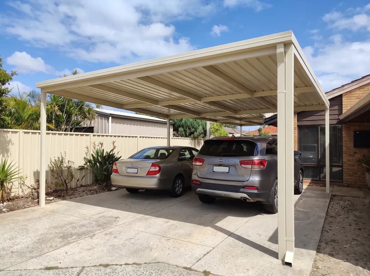 A double Colorbond carport in charcoal steel over a driveway at a Perth home, late afternoon